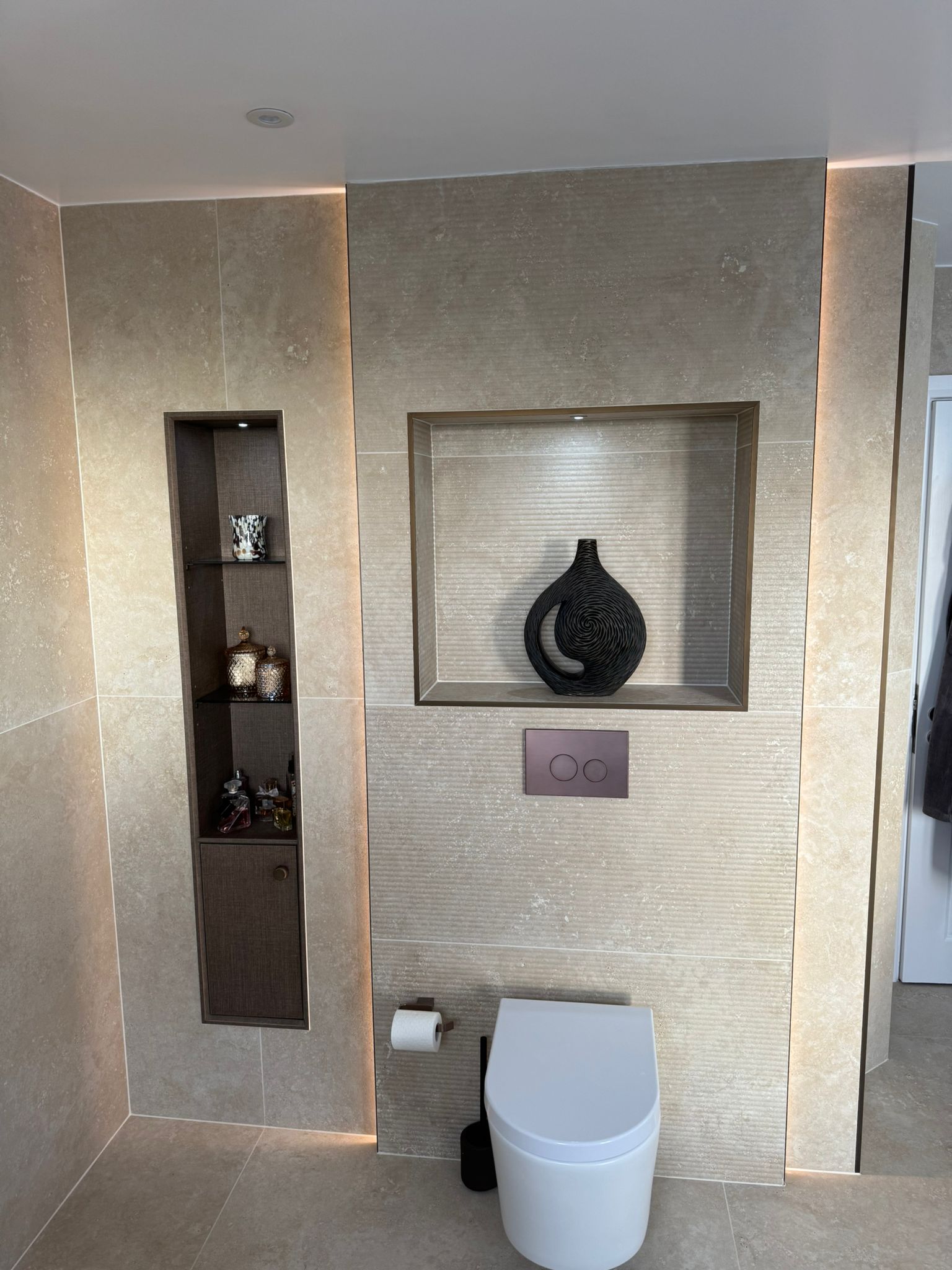 Luxury bathroom installation with wall-hung toilet, illuminated feature niches and bespoke storage by MDS