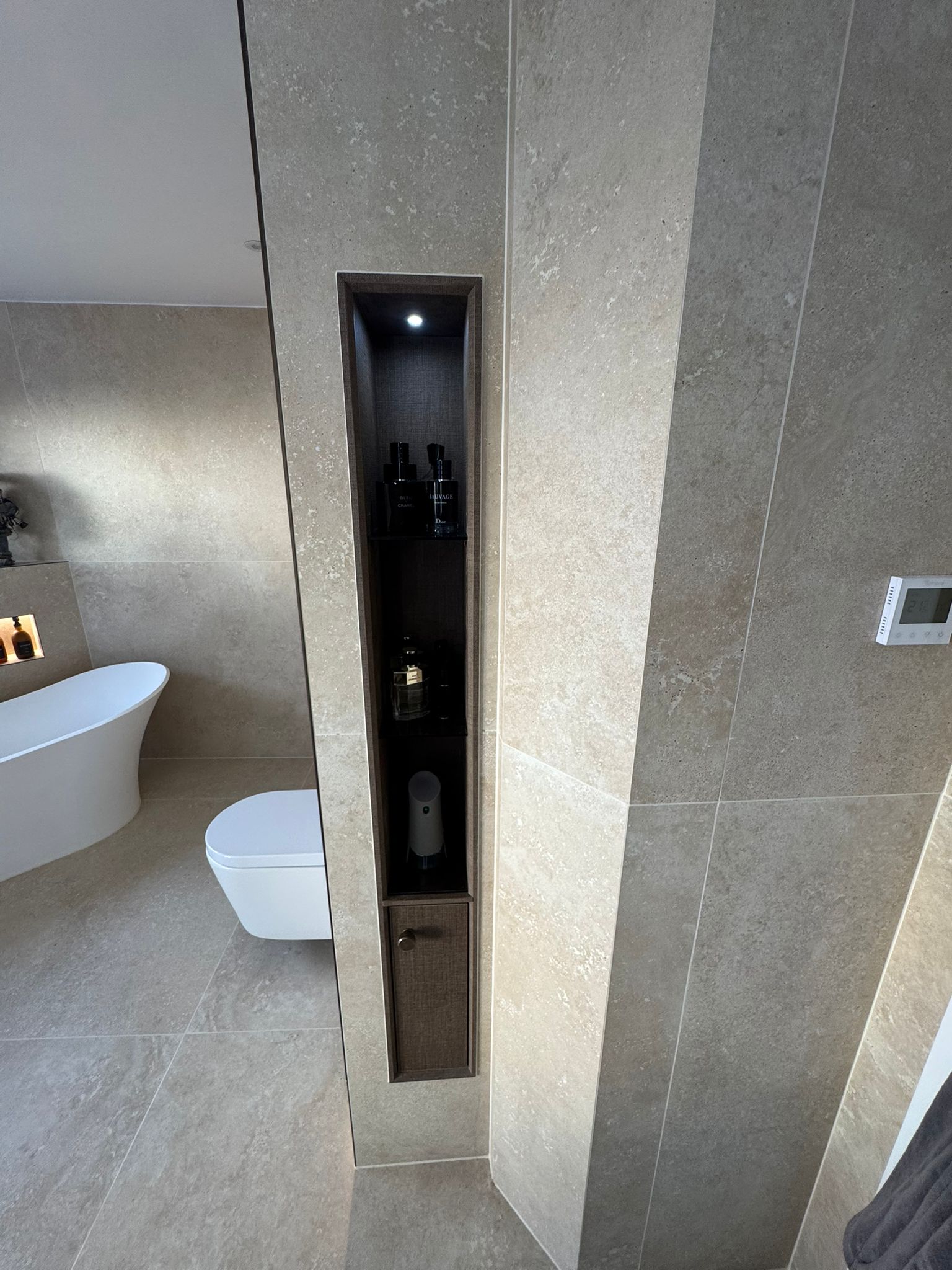 Luxury bathroom installation featuring illuminated recessed storage niche and stone-effect wall tiles by MDS Plumbing