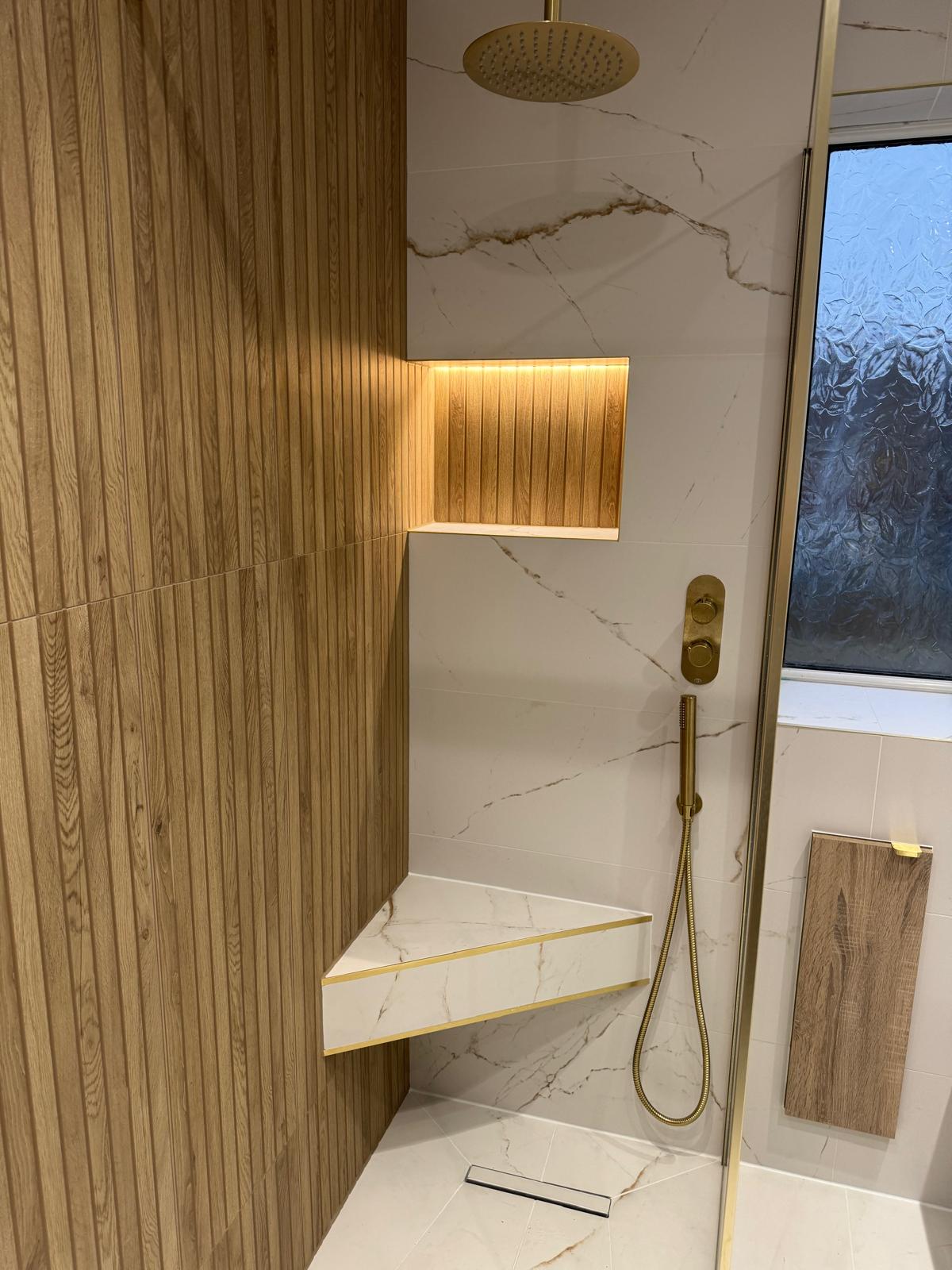 Luxury walk-in shower with illuminated niche, integrated seat and brushed brass fittings by MDS NE
